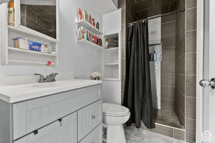 Vanity with integrated sink, medicine cabinet, built-in shelving, tiled shower stall, and recessed shower niche