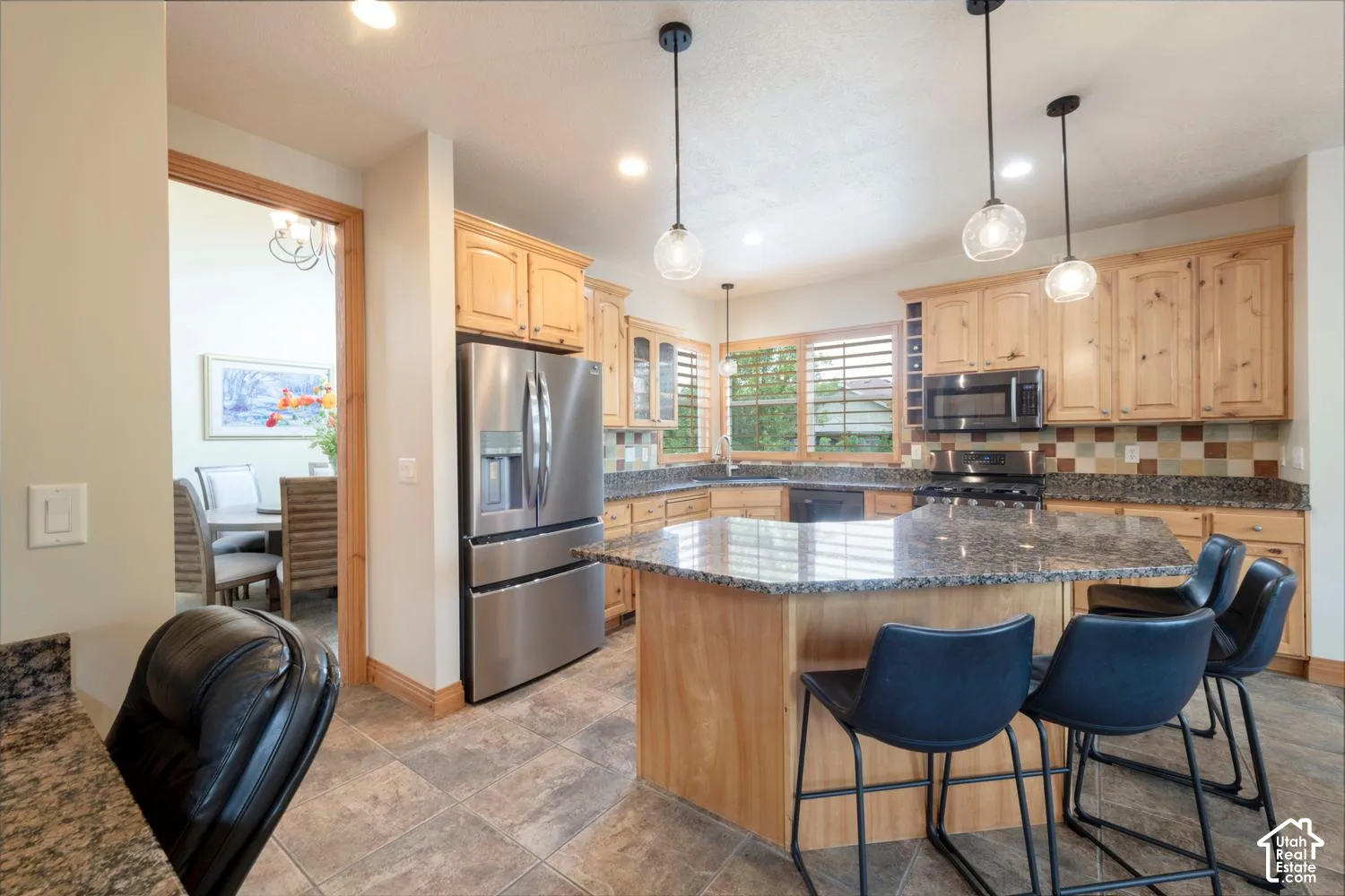 Kitchen featuring wood cabinetry, stainless steel refrigerator, dark countertops, tiled backsplash, and recessed lighting