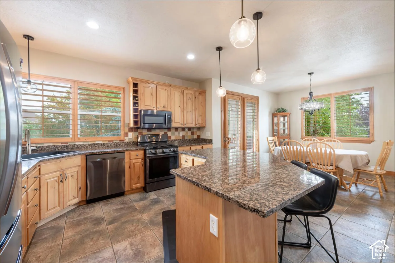Spacious kitchen featuring wood cabinetry, stainless steel appliances, granite countertops, and tile flooring