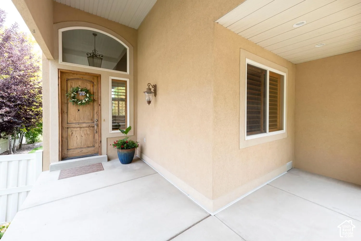 Stucco exterior with a covered porch featuring an arched transom window and a paneled wood entry door