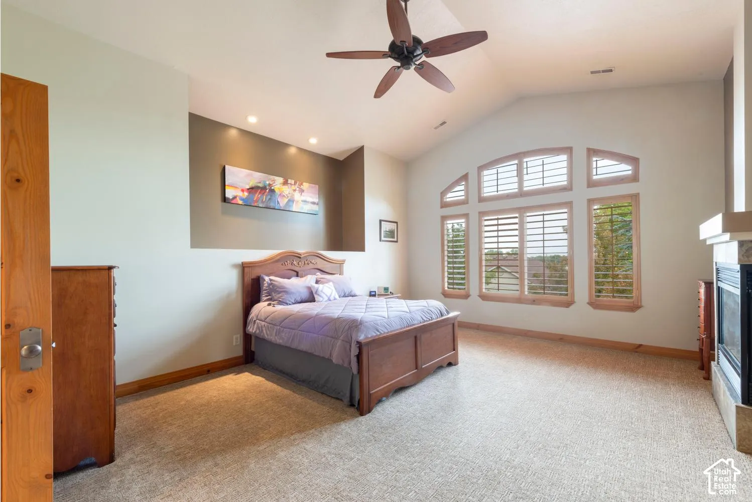 Vaulted ceiling with a ceiling fan, recessed lighting, and a prominent arched window with plantation shutters