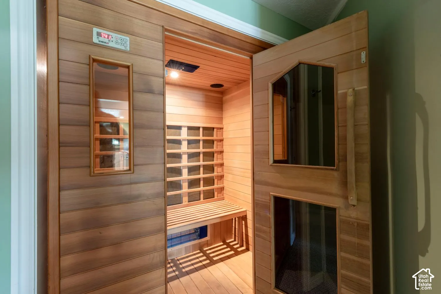 Wood-paneled sauna featuring a built-in bench, integrated lighting, and a digital control panel