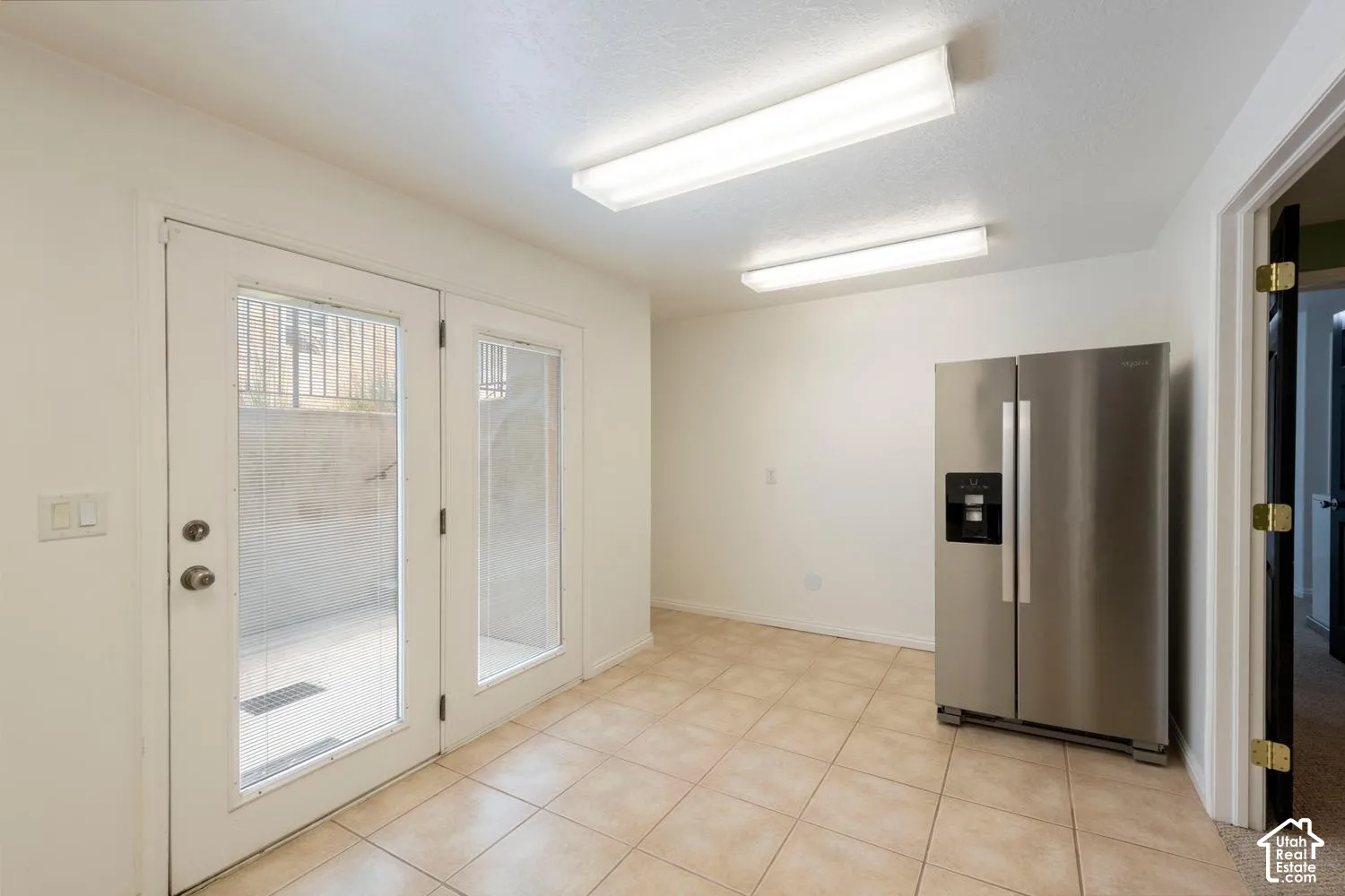 Ceramic tile flooring, white walls, and French doors with glass panels