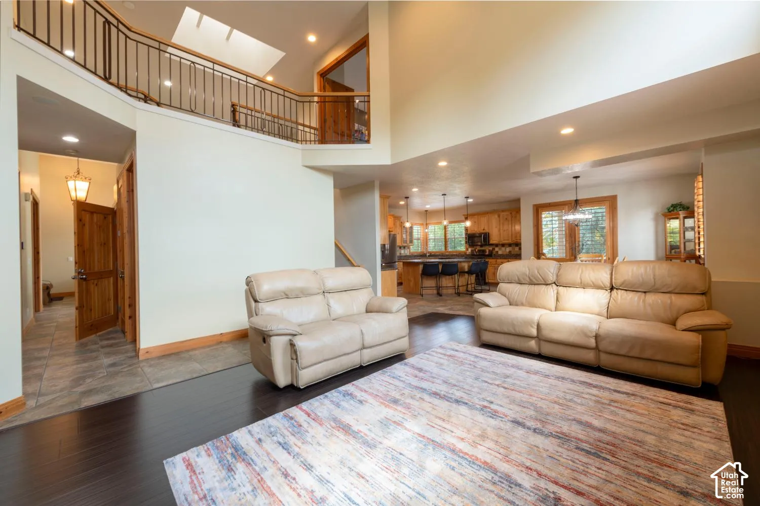 Two-story living area with dark wood-finish flooring, recessed lighting, and a skylight