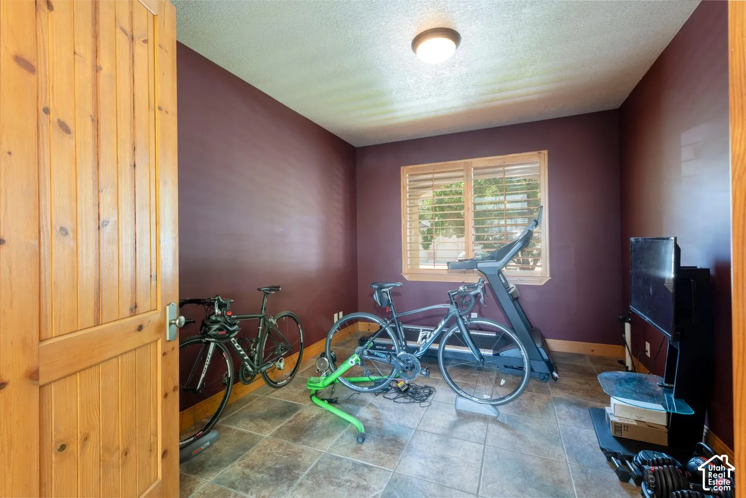 Room featuring a wood panel door, window with wood blinds, tile flooring, and a flush mount ceiling light