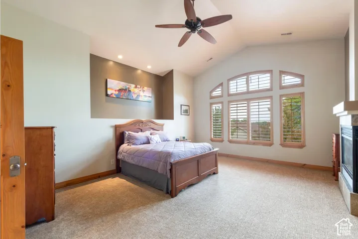 Vaulted ceiling with a ceiling fan, recessed lighting, and a prominent arched window with plantation shutters