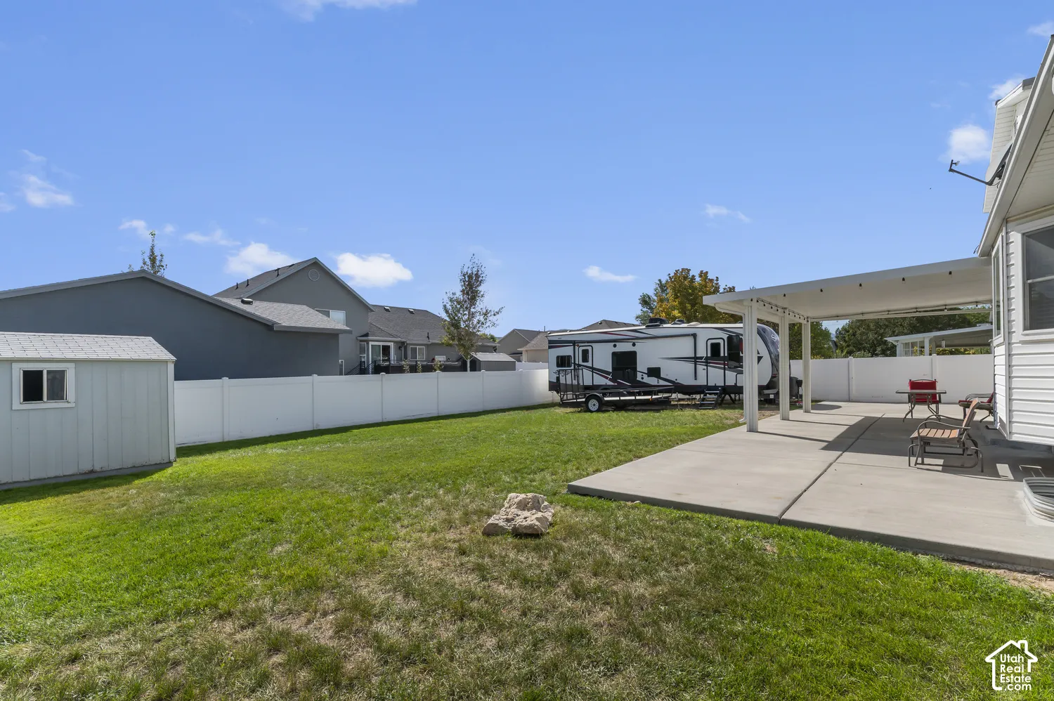 Expansive backyard with a concrete patio, white pergola, storage shed, and a privacy fence