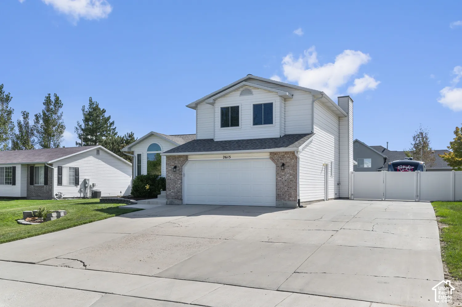 Two-story property featuring a two-car garage, brick facade accents, and a wide concrete driveway