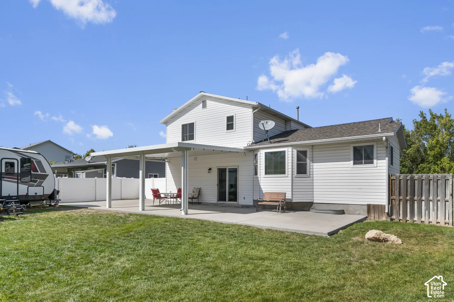 Expansive rear yard featuring a covered patio, additional concrete patio space, and a wood privacy fence