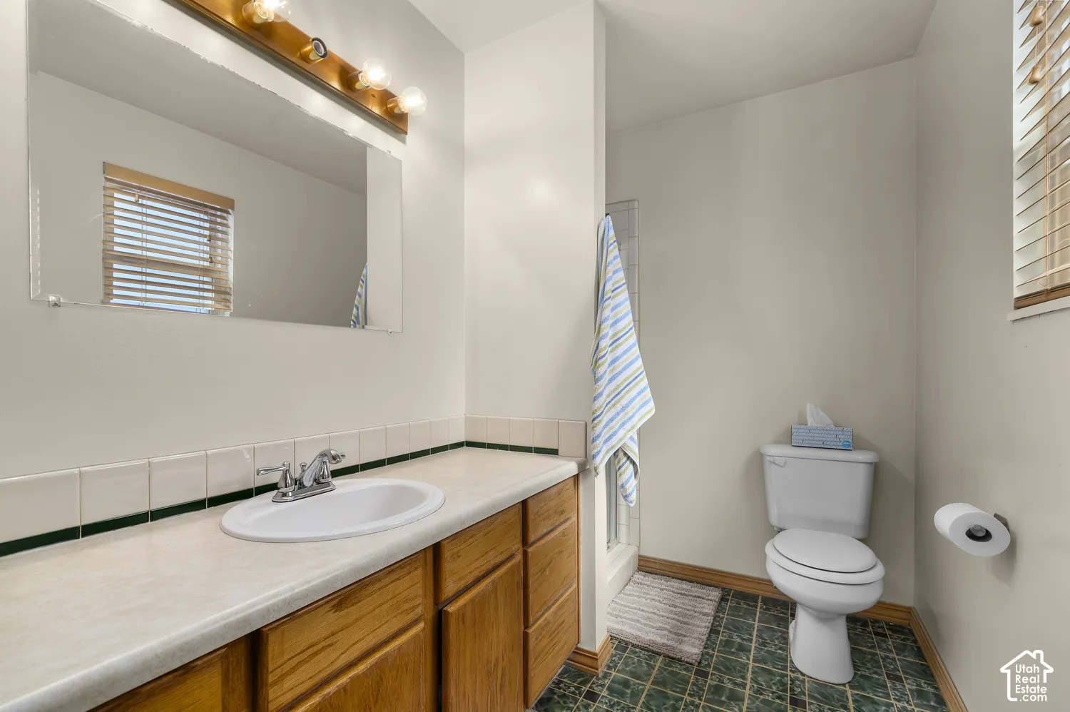 Bathroom with a wood-finish vanity, integrated sink, and chrome faucet