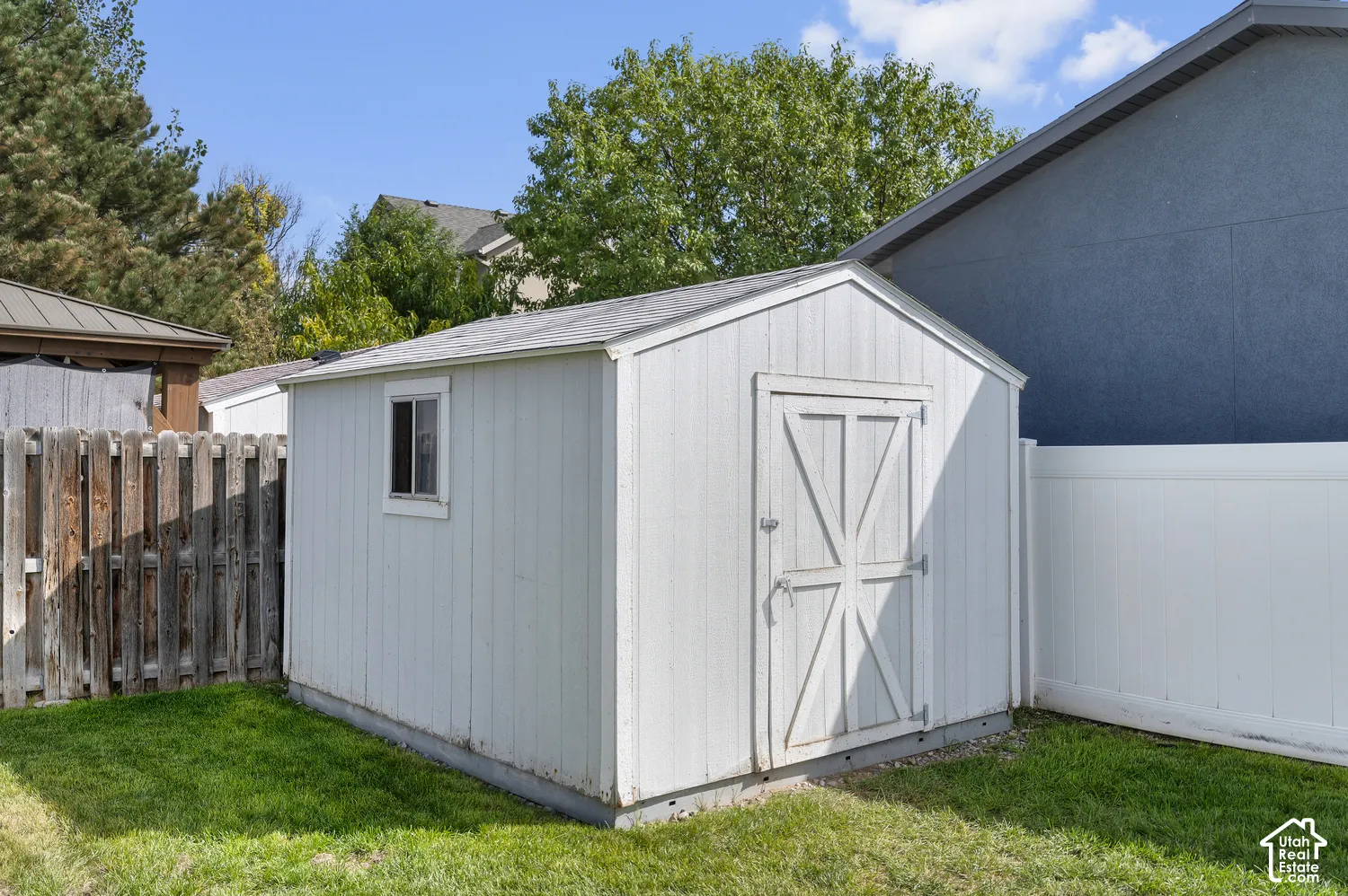 White wooden Tuff shed with a gable roof, cross-braced door, and a single window