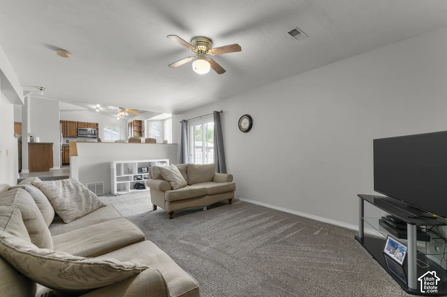 Carpeted living area with a ceiling fan light fixture