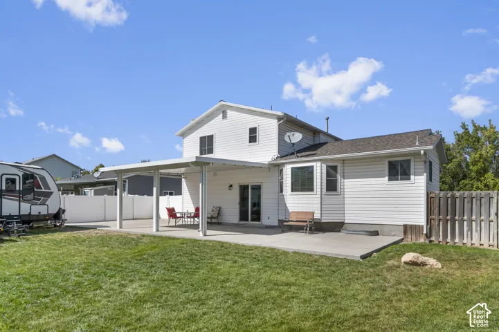 Expansive rear yard featuring a covered patio, additional concrete patio space, and a wood privacy fence