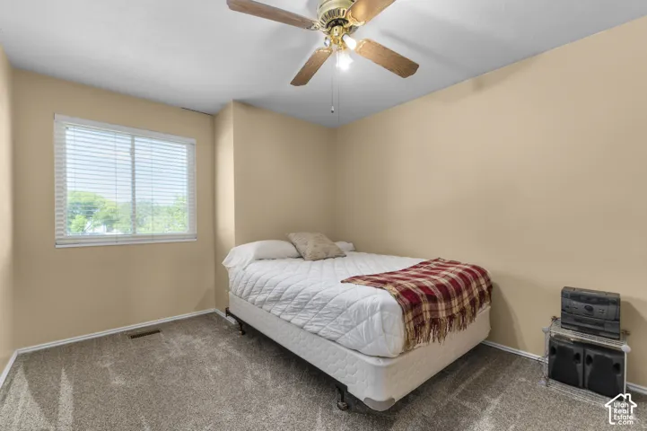 Wall-to-wall carpeting, window with blinds, ceiling fan with light, and neutral wall paint