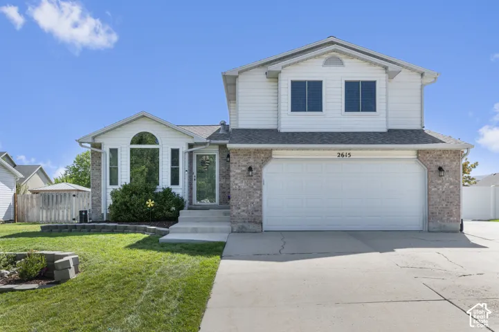 Two-story residence featuring a partial brick facade, attached two-car garage, and a concrete driveway