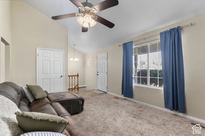 Vaulted ceilings, a ceiling fan with integrated lighting, window with grid panes, and neutral wall tones