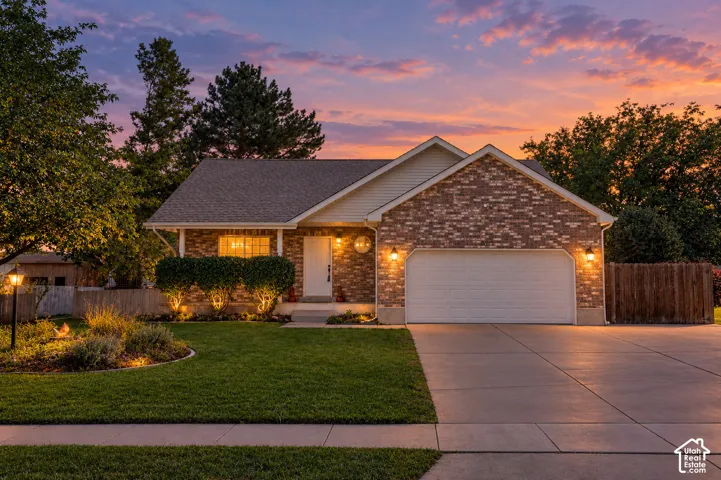 Brick and siding exterior, attached garage, concrete driveway, manicured lawn, and established landscaping