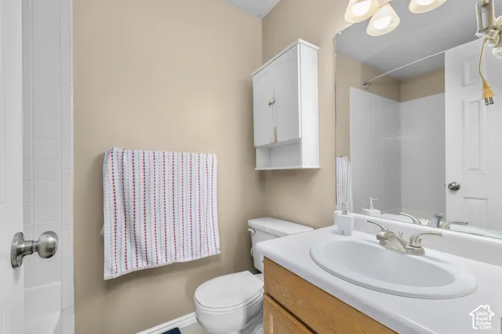 Bathroom featuring a white sink, wood-finish vanity, white countertop, and wall-mounted storage cabinet