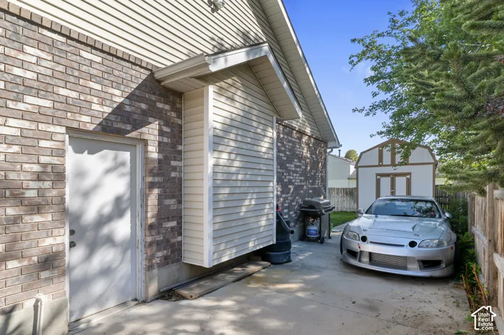 Brick exterior with a white door, concrete pathway, and a detached shed