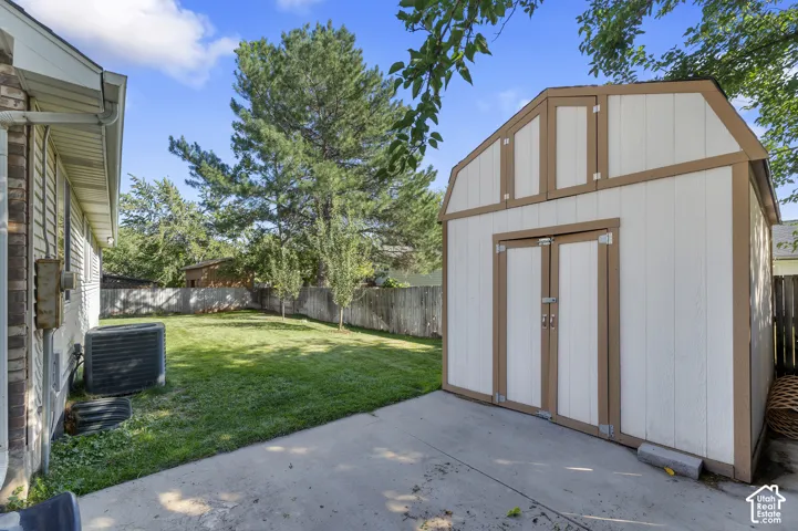 Expansive green lawn, concrete patio, and a gambrel-roof storage shed with double doors