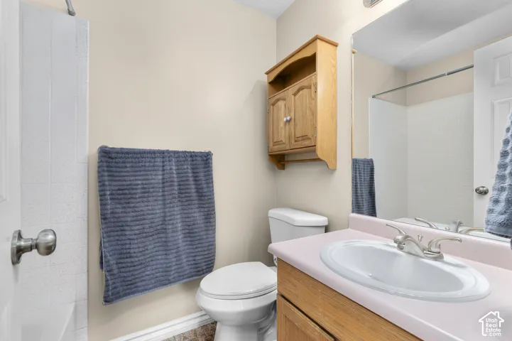 Vanity with integrated sink, wood-finish cabinetry, and wall-mounted mirror