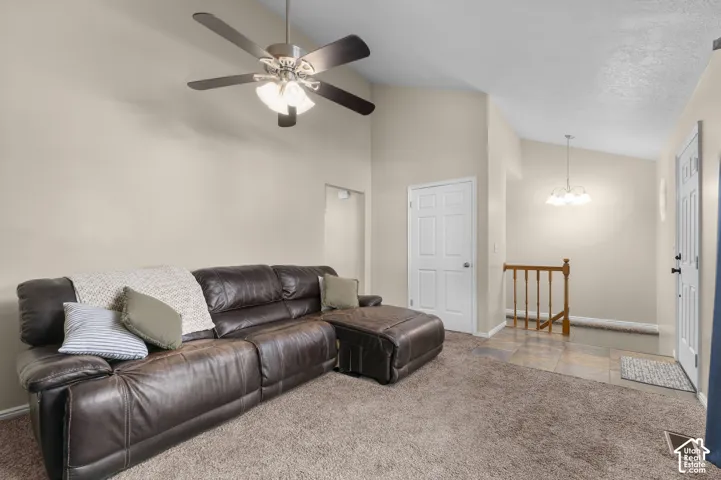Vaulted ceilings, a ceiling fan with integrated lighting, and carpeted flooring