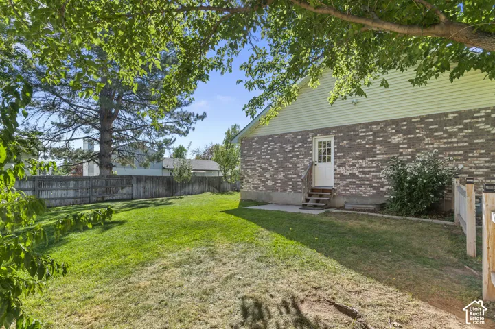 Expansive backyard featuring a manicured lawn, mature trees, and a wooden privacy fence