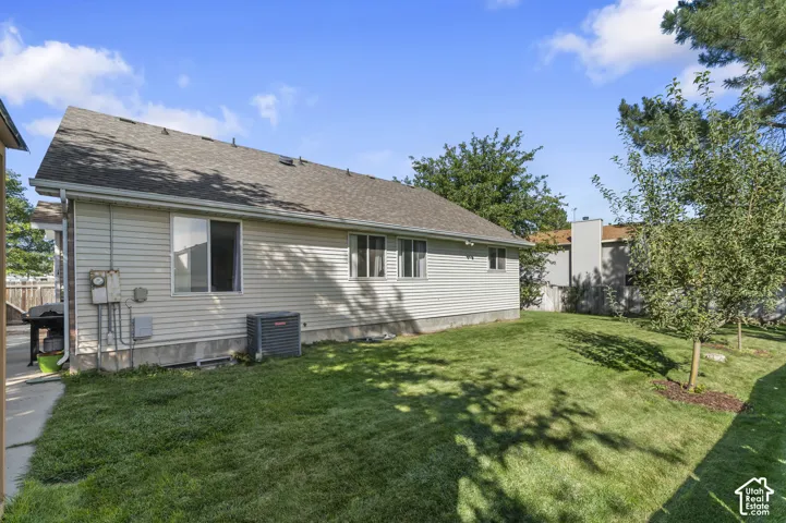 Expansive lawn area with young trees, exterior siding, and a visible HVAC unit