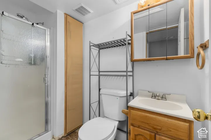 Enclosed shower with clear and frosted glass, wood-finish vanity with an integrated sink, and an overhead mirrored medicine cabinet