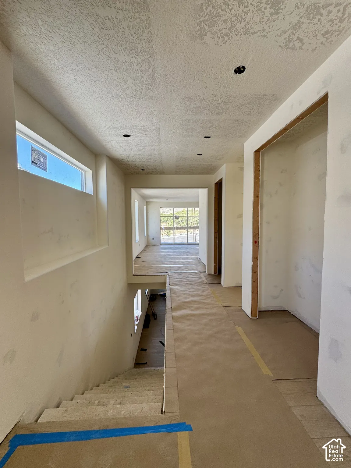 Recessed ceiling lighting, horizontal window, open doorways, and an interior staircase