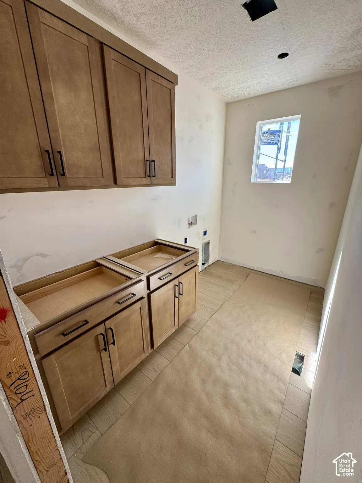 Wood-finish cabinetry with black hardware, tiled flooring, and a single window