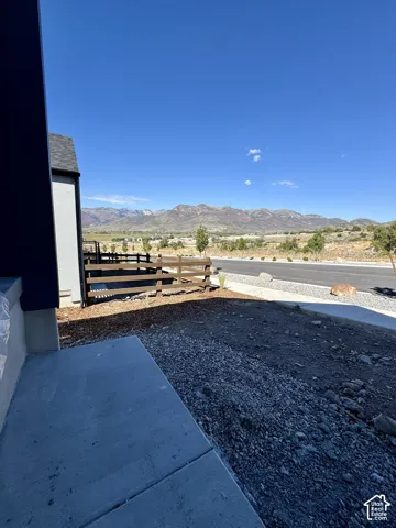 Paved concrete walkway with a partially completed exterior, featuring a wood fence, and a backdrop of distant mountains