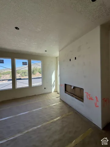 Three large windows, built-in fireplace opening, recessed ceiling lighting, and textured ceilings