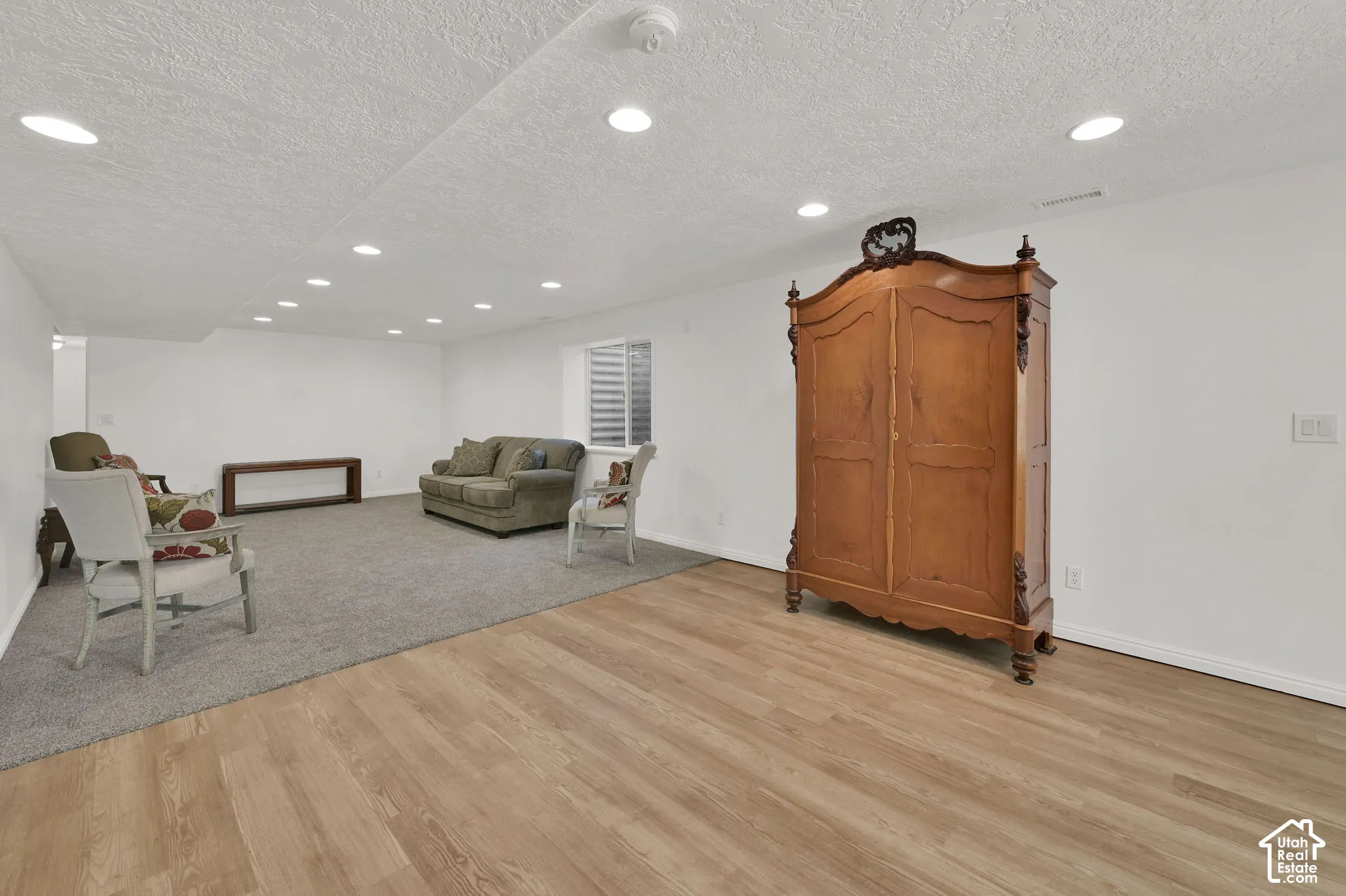 Recessed lighting, wood-finish flooring, light gray carpeting, and a window with horizontal blinds
