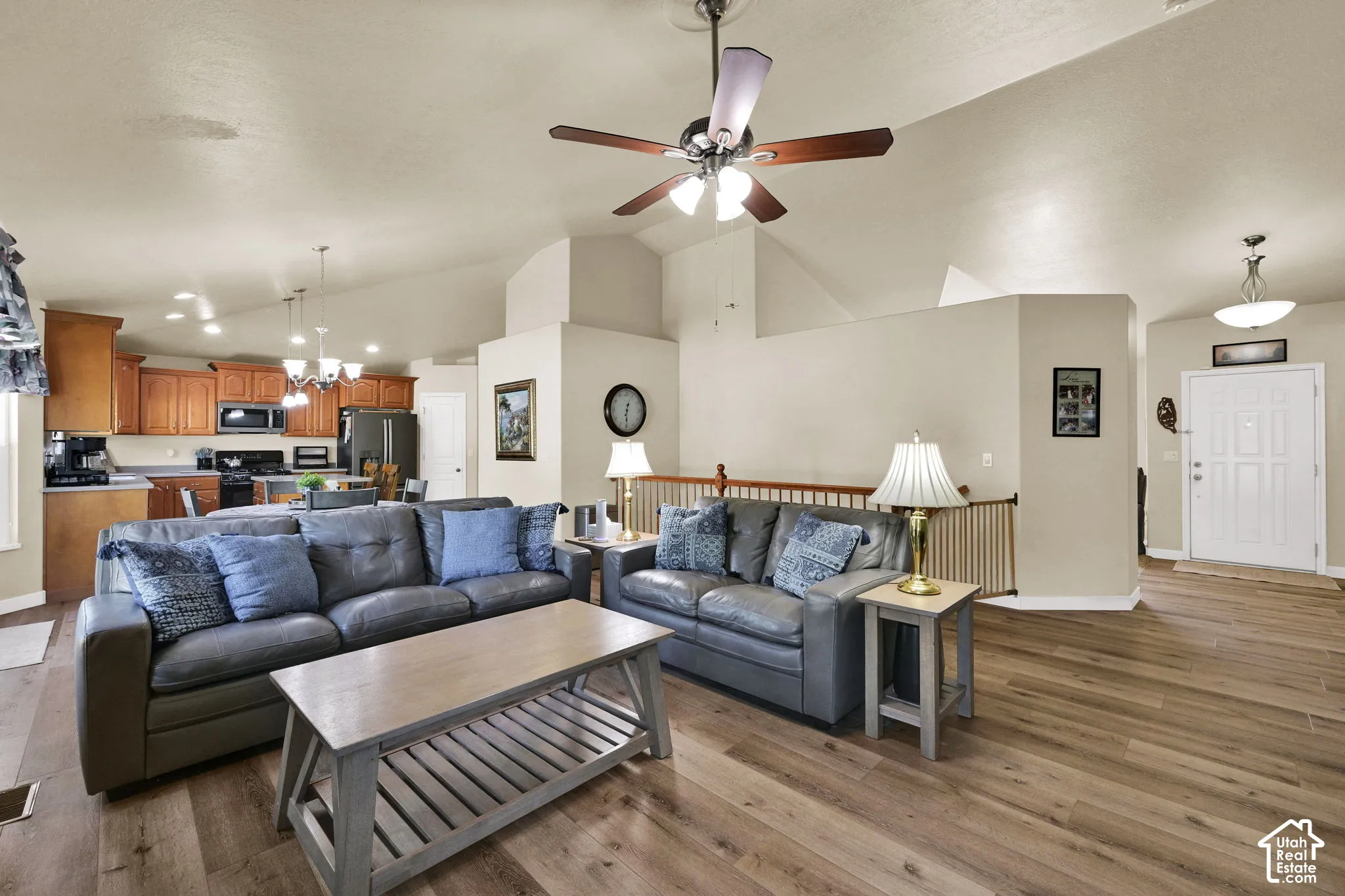 Open-concept living space featuring wood-finish flooring, vaulted ceilings, and a ceiling fan with integrated lighting