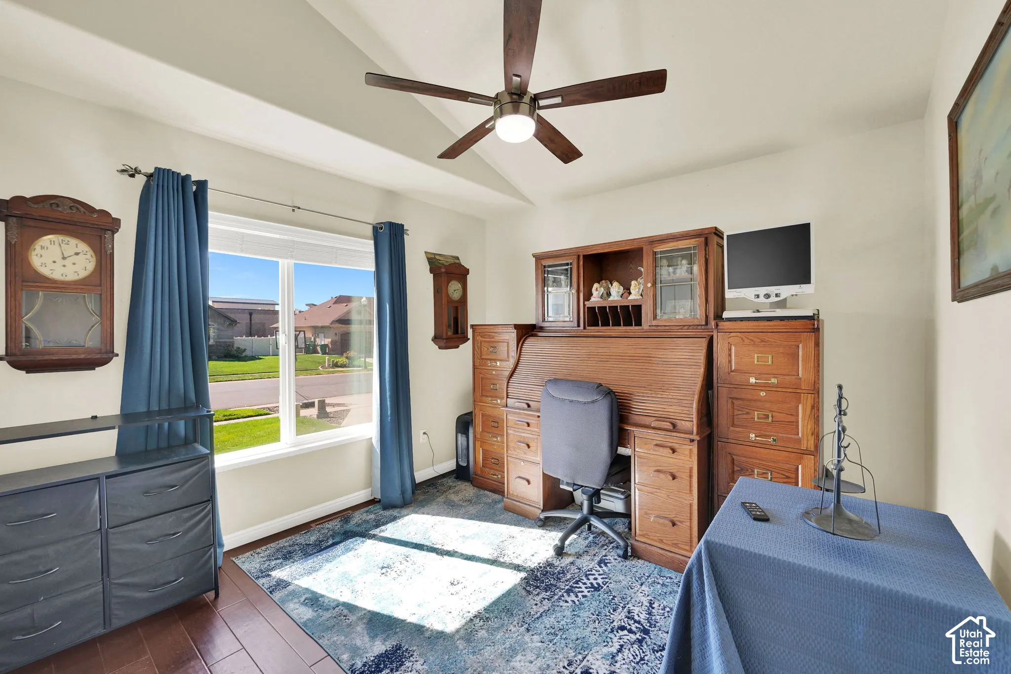 Vaulted ceiling with a ceiling fan, large window, and wood-finish flooring