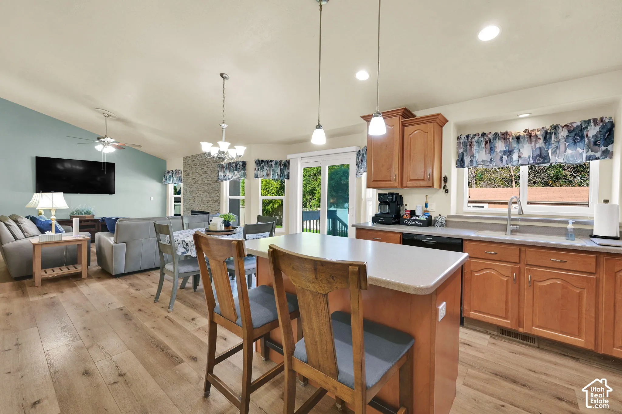 Open-concept living space featuring wood-finish flooring, a kitchen island with seating, pendant lighting, and direct access to an outdoor area