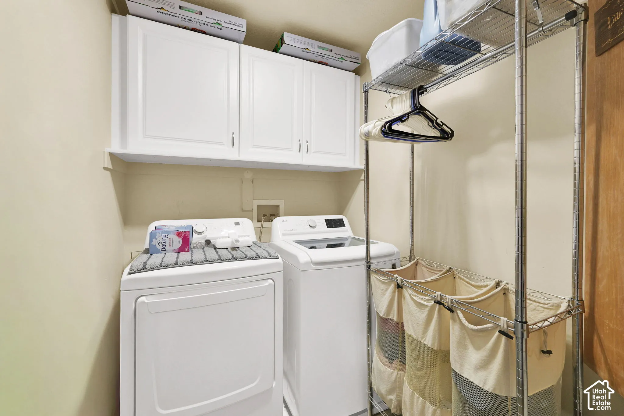 Laundry area with white upper cabinetry and a chrome shelving unit