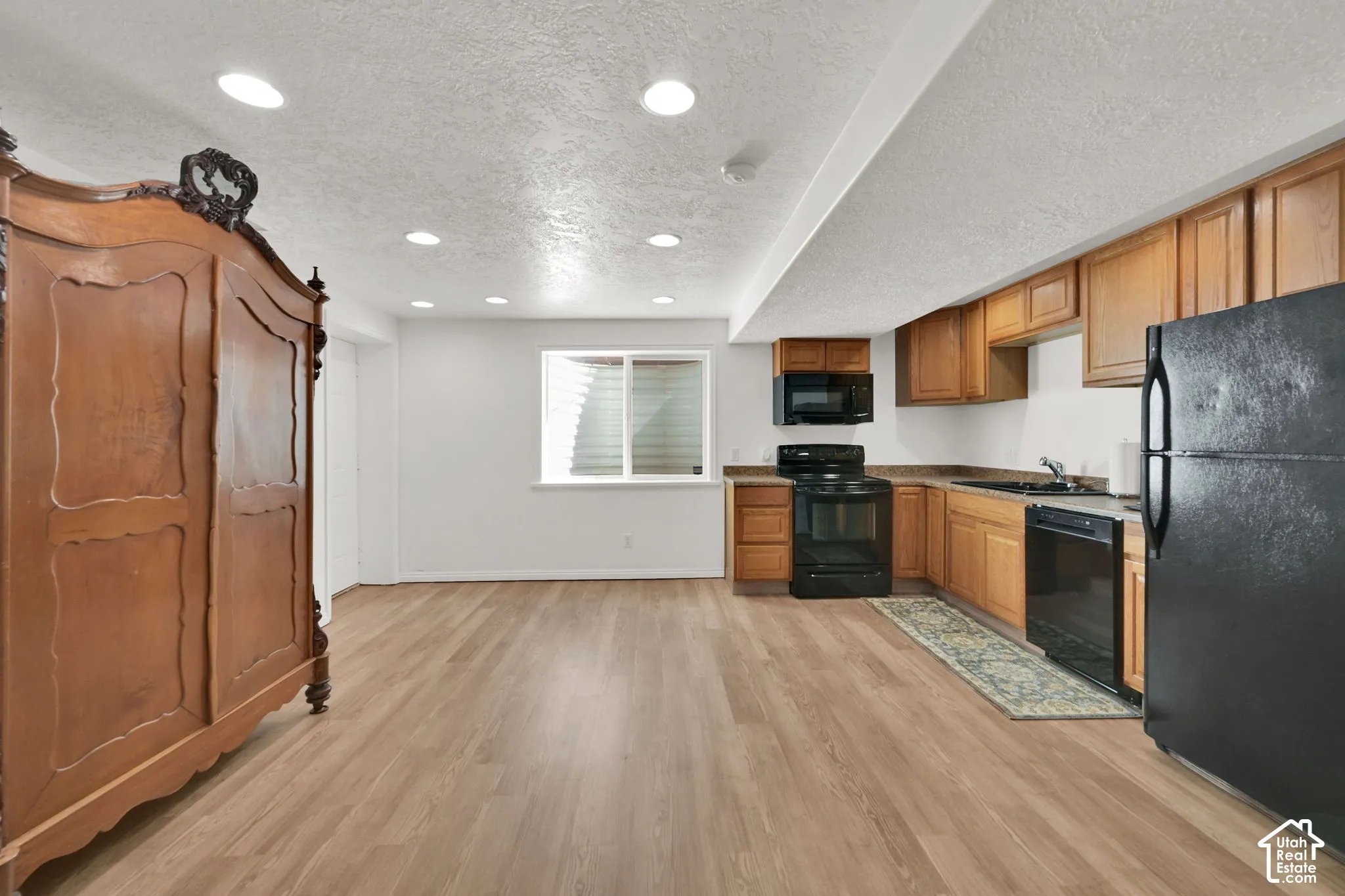 Kitchenette featuring wood-finish flooring, recessed lighting, wood cabinetry, and black appliances