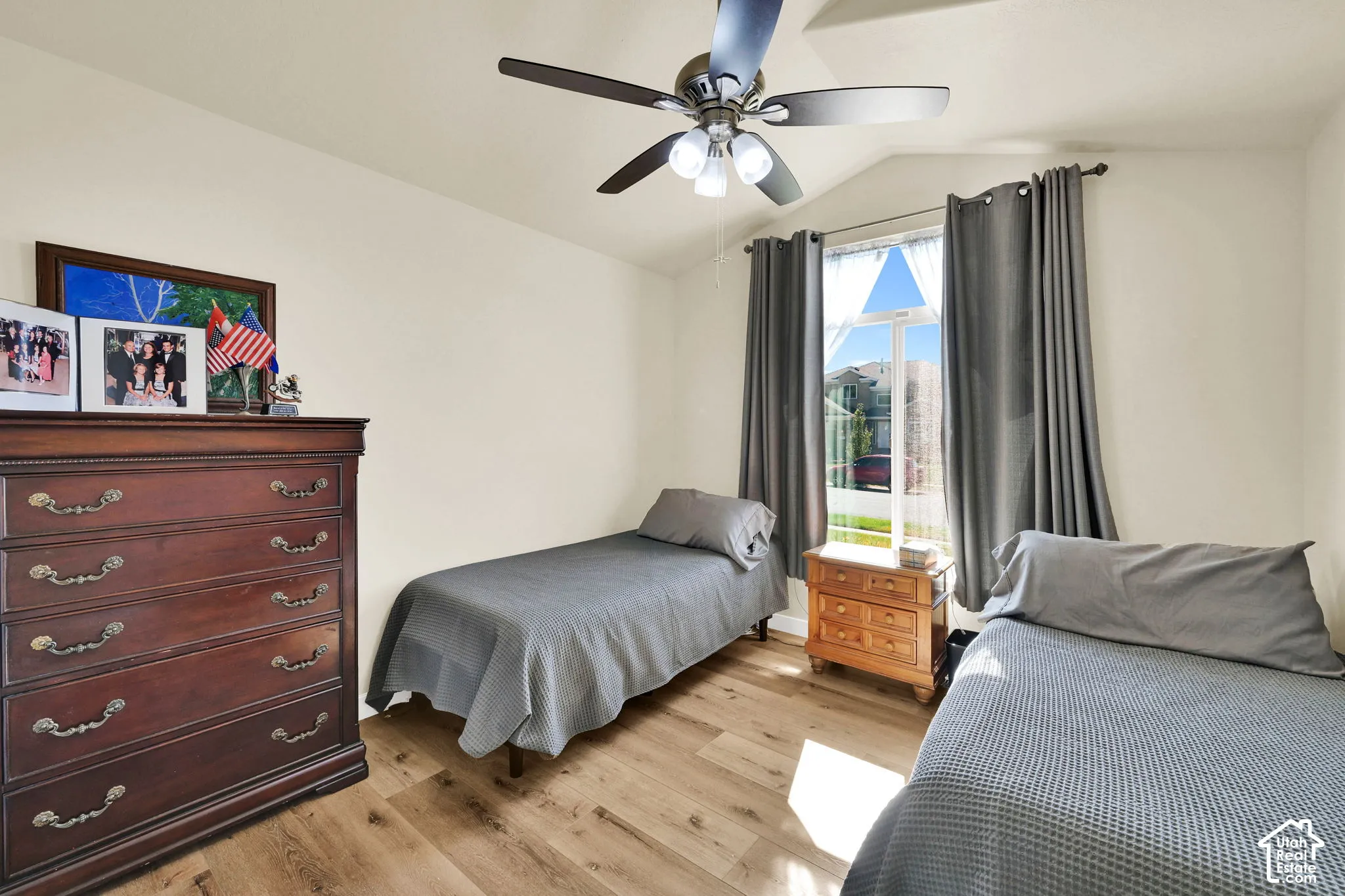 Vaulted ceiling featuring a ceiling fan with integrated lighting, wood-finish flooring, and a large window