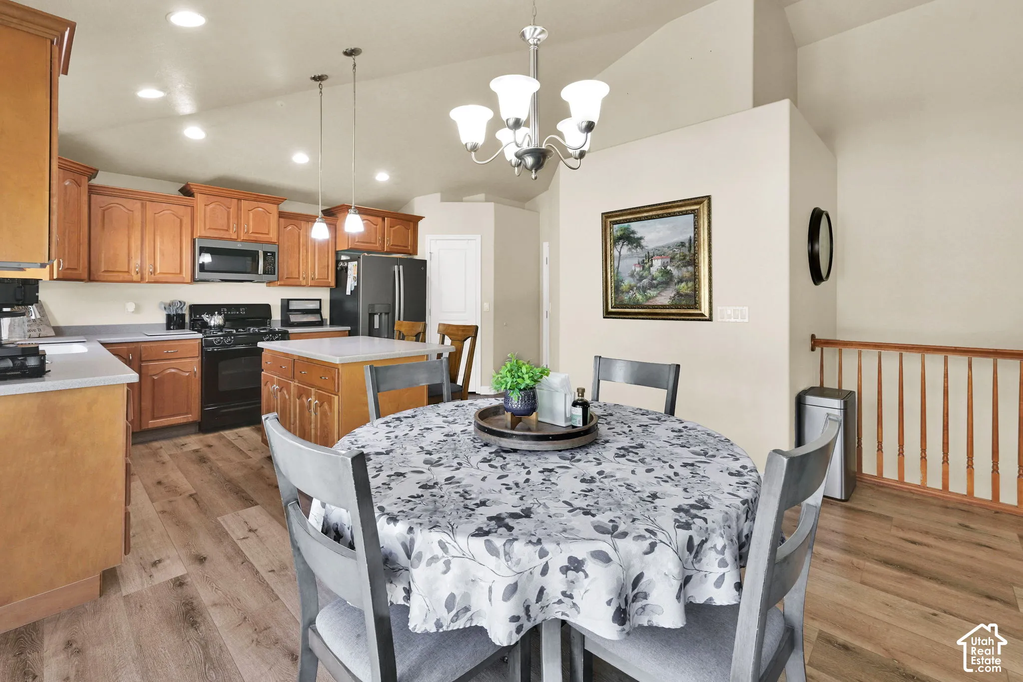 Kitchen and dining area featuring wood-finish flooring, vaulted ceilings, recessed lighting, and a kitchen island
