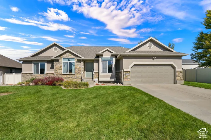 Stucco and stone exterior with an attached two-car garage, concrete driveway, and front landscaping