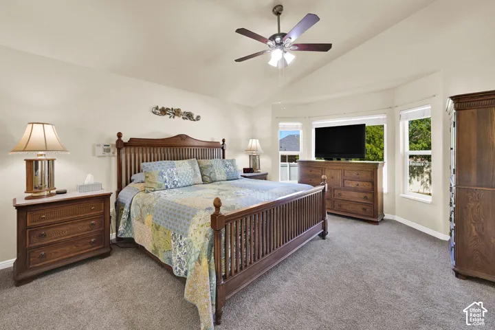 Vaulted ceiling, ceiling fan, carpeting, bay window, and light-colored walls