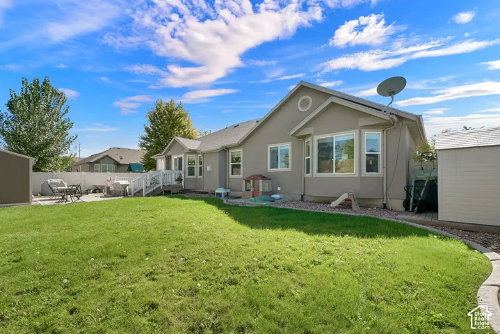 Expansive lawn area, concrete patio, white vinyl fencing, and two storage sheds
