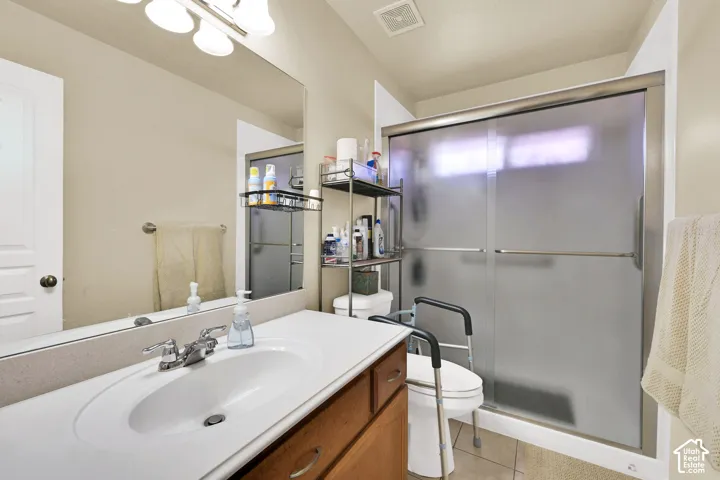 Bathroom featuring a single vanity with an integrated sink, polished chrome faucet, a large wall-mounted mirror, and a shower with frosted sliding glass doors