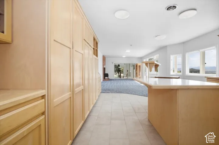 Extensive light wood cabinetry with built-in storage, tile flooring, and a stone-finish countertop