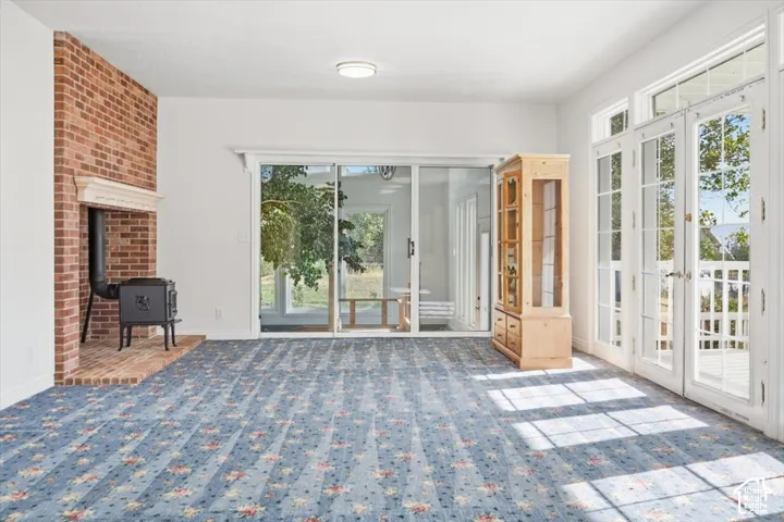 Brick fireplace with wood-burning stove, white mantel, glass sliding door, and white French doors