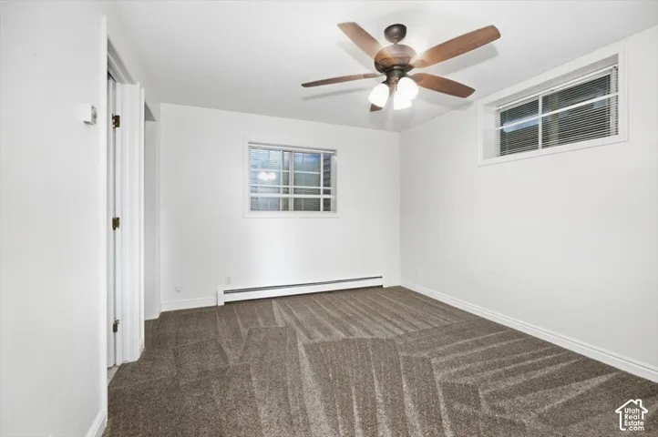 Neutral-toned carpeting, white walls, two windows with horizontal blinds, and a ceiling fan with integrated lighting