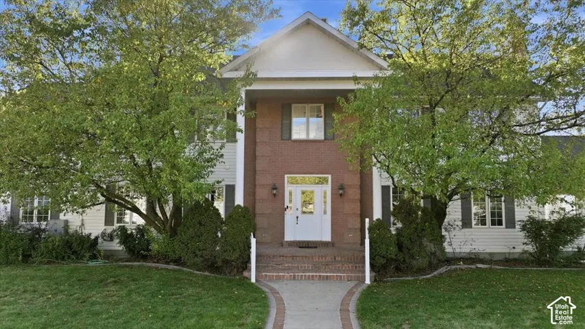 Brick and siding exterior with a prominent portico, arched entryway, and a winding paver pathway