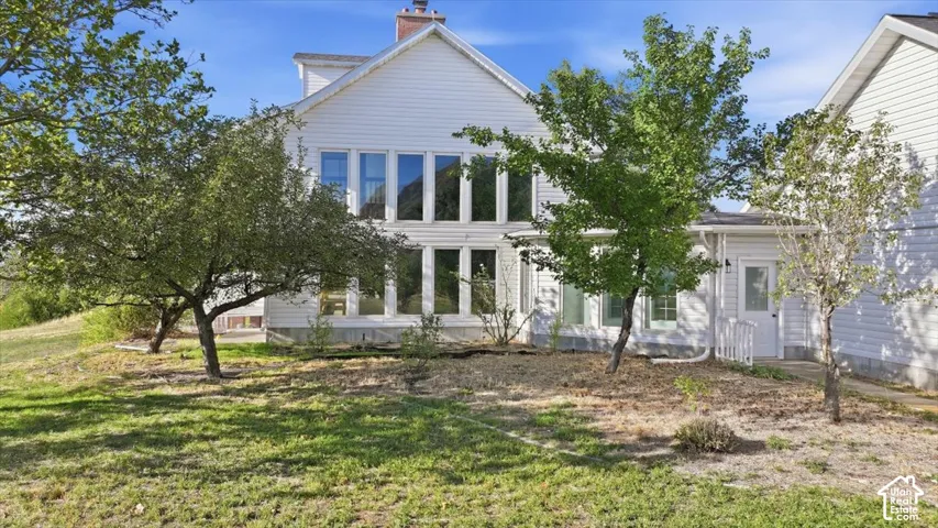 White siding exterior with multiple windows, a prominent chimney, and a small side entrance